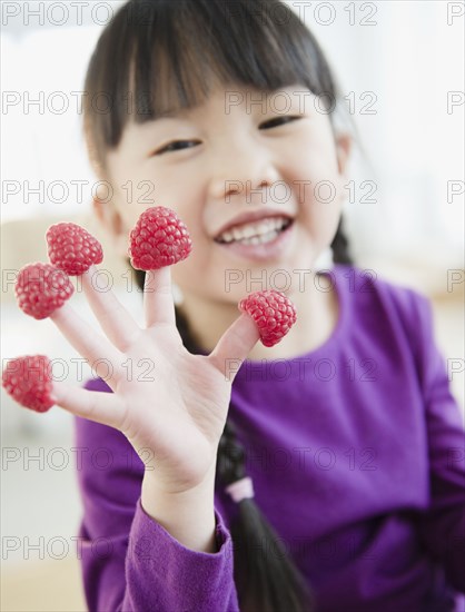 Chinese girl with raspberries on fingers