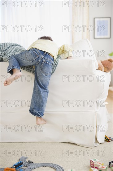 Black boy climbing over back of sofa