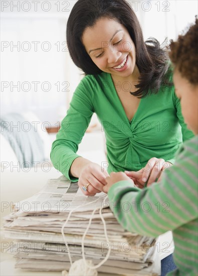 Mixed race mother and son recycling newspapers