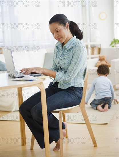 Mixed race mother typing on laptop