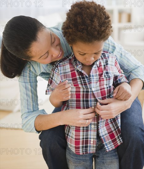 Mixed race mother helping son to dress