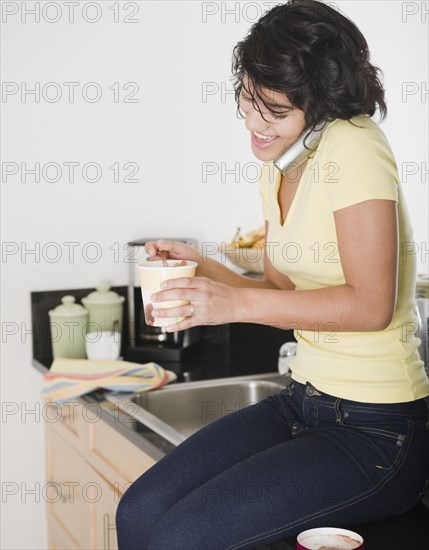 Hispanic woman eating ice cream and talking on cell phone