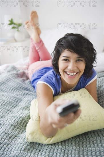 Hispanic woman changing channel on television