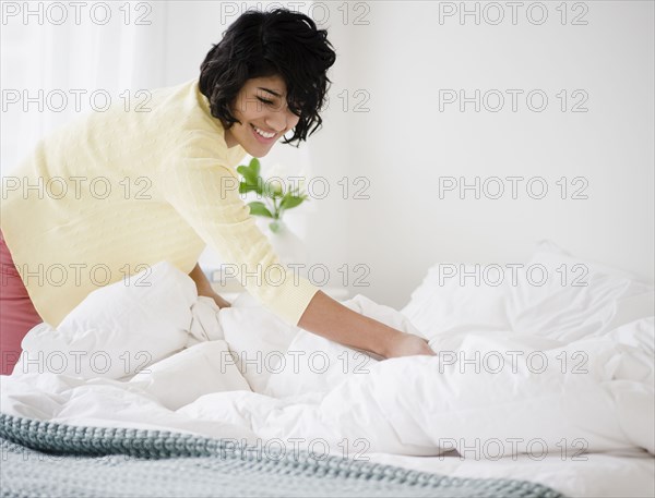 Hispanic woman making bed