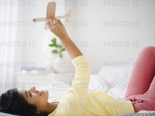 Hispanic woman playing with toy airplane