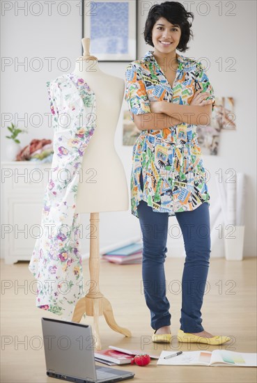 Hispanic woman standing with dressmaker's dummy