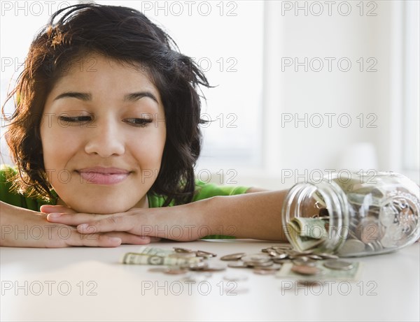 Hispanic woman looking at change in glass jar