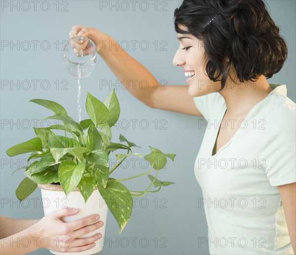 Hispanic woman watering plant