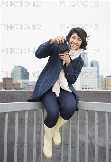 Hispanic woman taking photographs in city