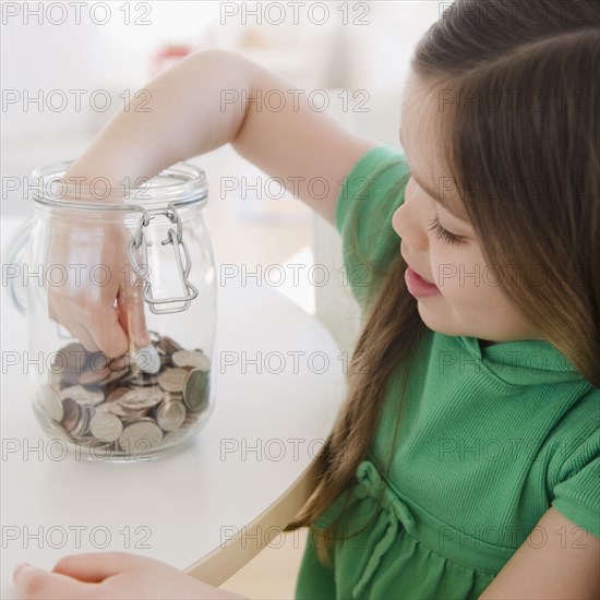 Mixed race girl taking coin out of jar