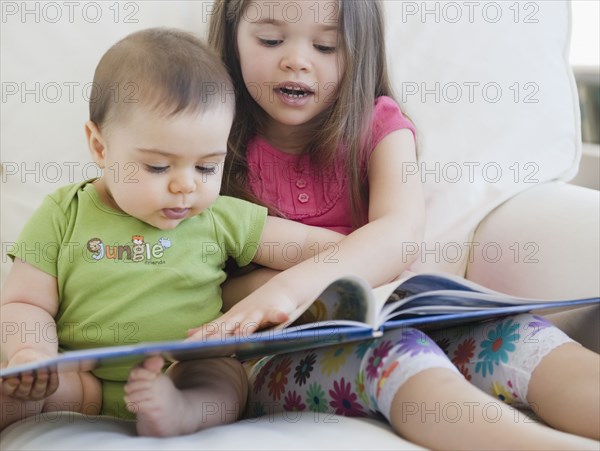 Mixed race girl reading story to brother