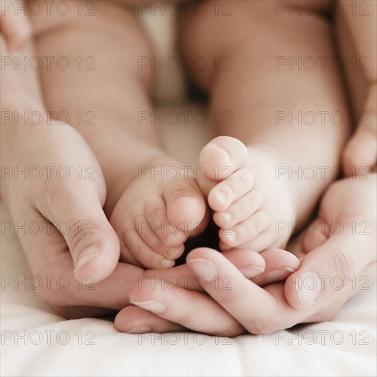 Mother holding mixed race baby boy's feet