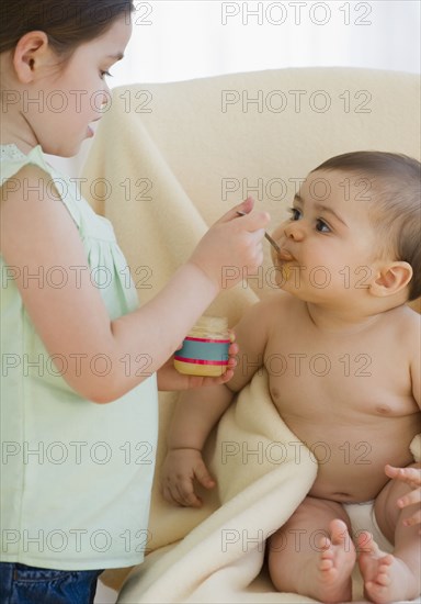 Mixed race girl feeding baby brother