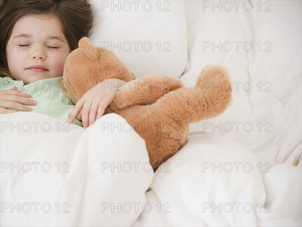 Mixed race girl sleeping with teddy bear