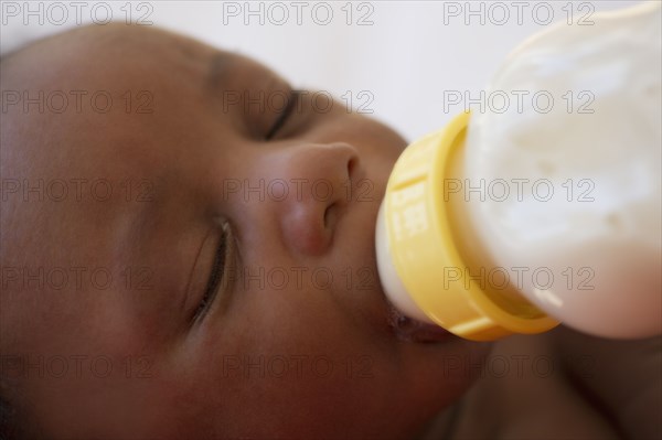 Newborn Black baby drinking from bottle