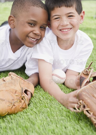 Boys laying in grass with baseball and baseball gloves