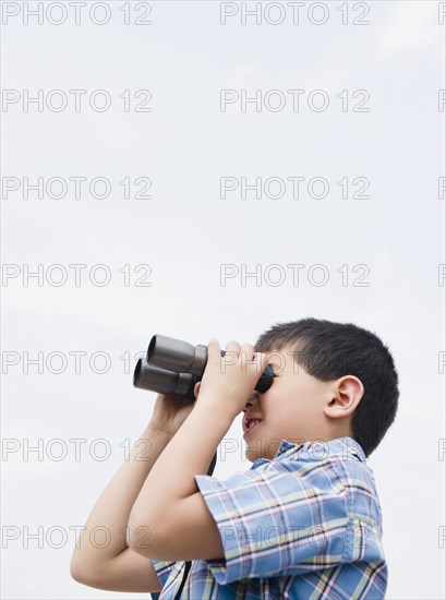 Mixed race boy looking through binoculars