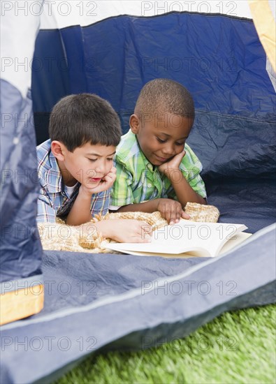 Boys reading book in tent