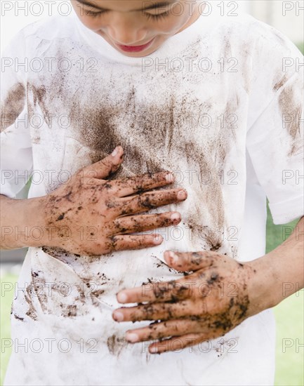 Mixed race boy wiping messy hands on shirt