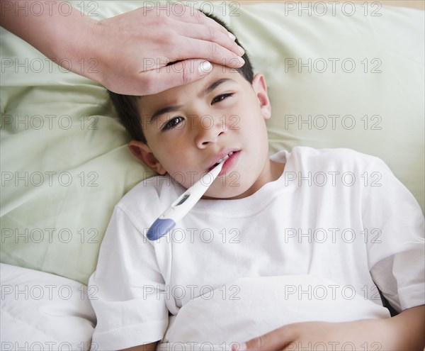 Sick mixed race boy having is temperature taken