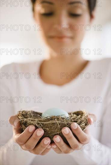 Mixed race woman holding nest with egg