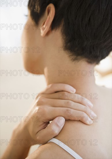 Mixed race woman rubbing neck and shoulder