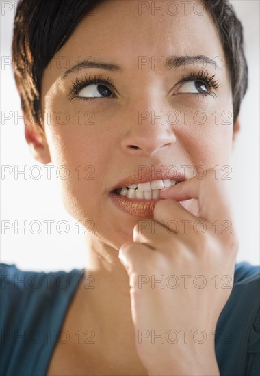 Mixed race woman with short hair biting fingernail