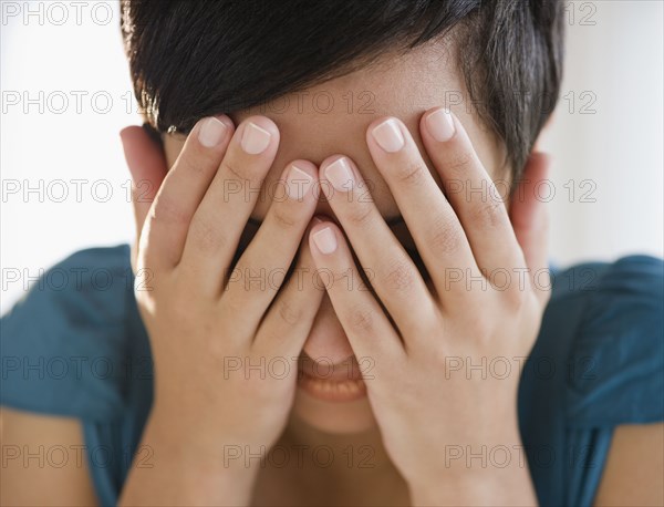 Mixed race woman covering face with hands