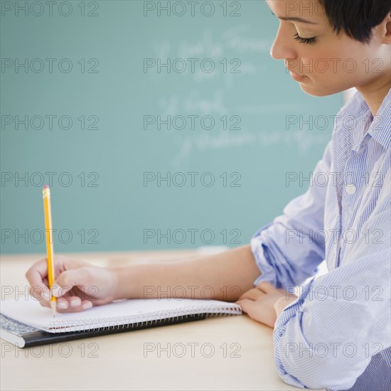 Mixed race woman writing in notebook