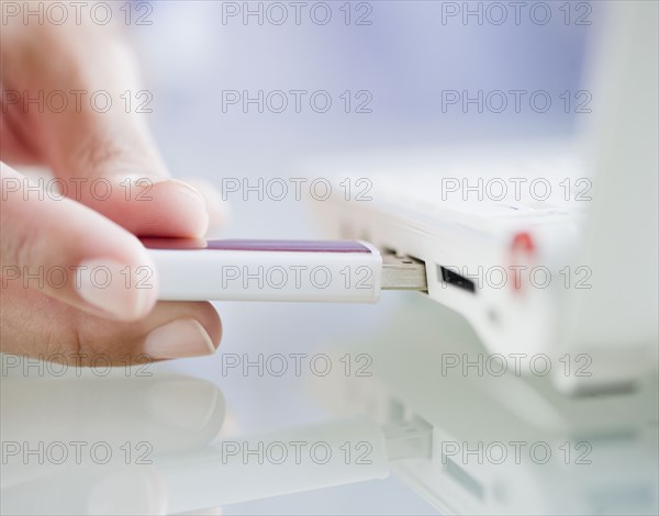 Hand pushing USB stick into laptop