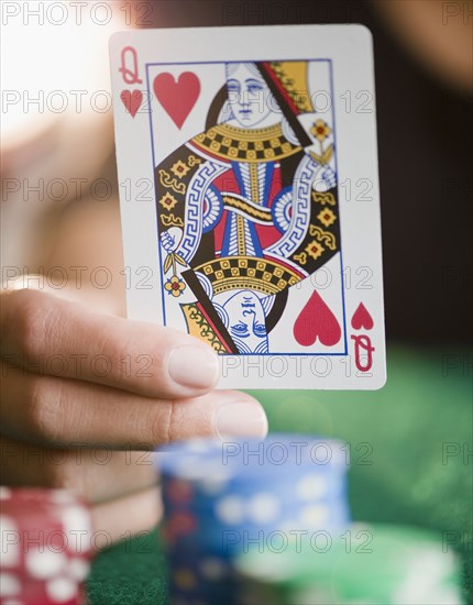 Hand holding queen of hearts playing card