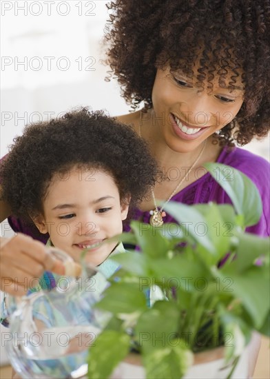Mother and daughter watering potted plant