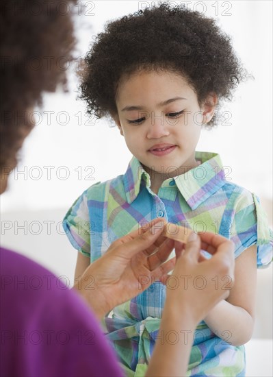 Mother putting bandage on finger of daughter