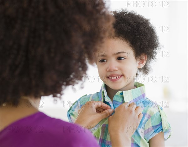 Mother buttoning shirt of daughter