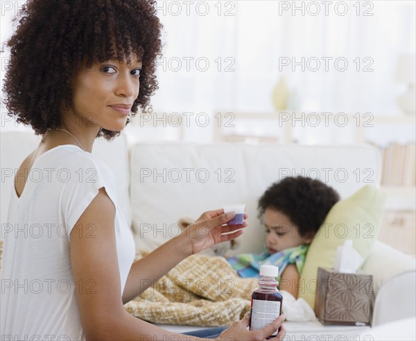 Mother giving cough syrup to sick daughter