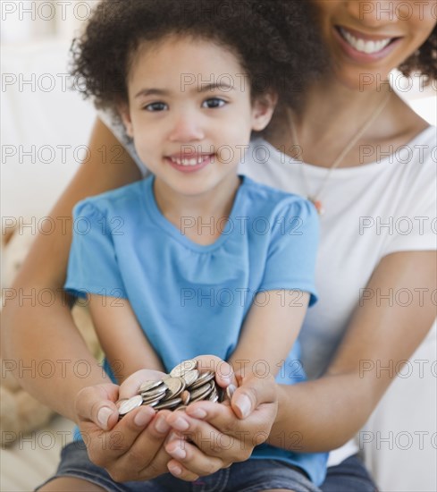 Mother and daughter cupping coins in hands