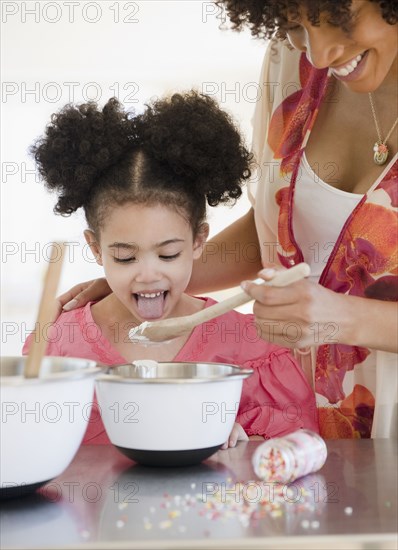 Mother feeding daughter from mixing bowl