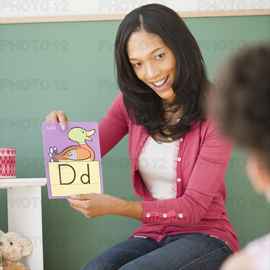 Black teacher showing letter d flash card to student