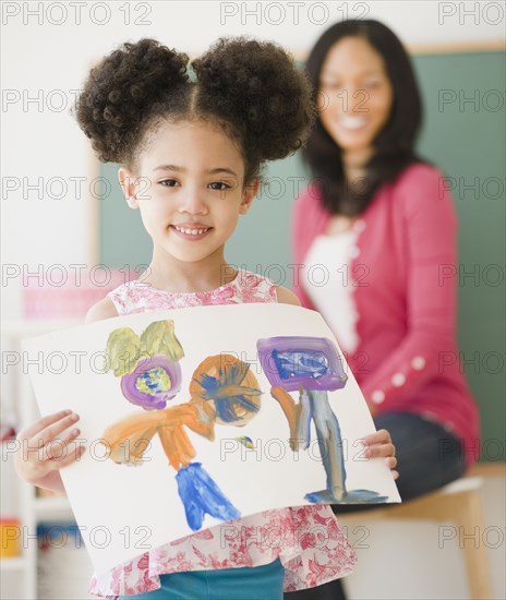 Proud student holding painting in classroom