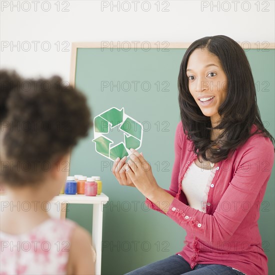 Teacher showing recycling symbol to student