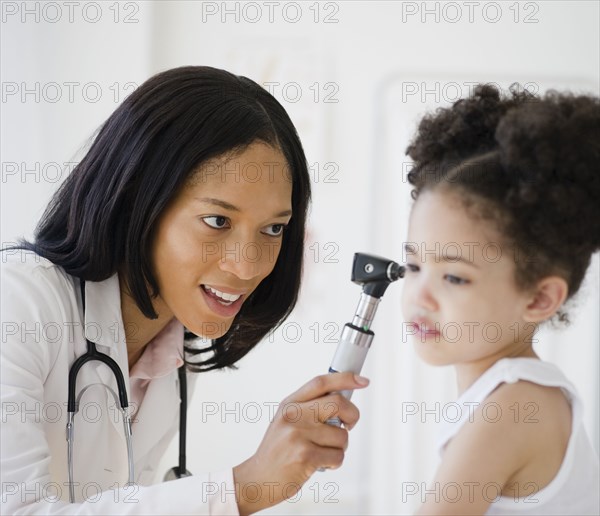 Pediatrician with otoscope examining patient