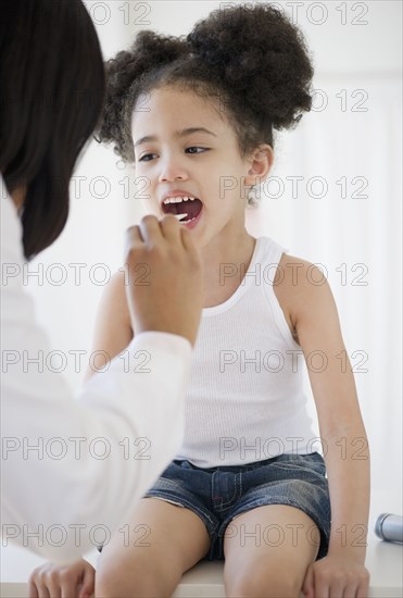 Pediatrician with tongue depressor examining patient