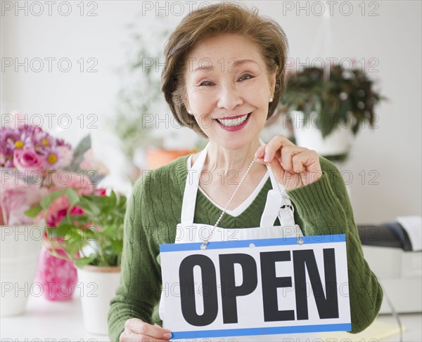 Japanese florist holding open sign