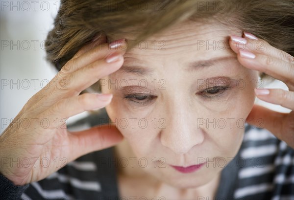 Sad Japanese woman with head in hands