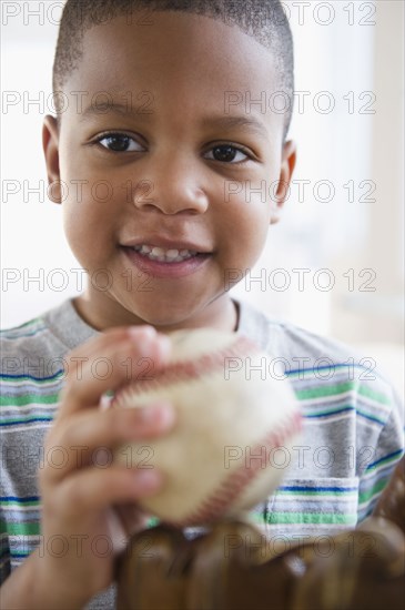 African American boy holding baseball and baseball glove