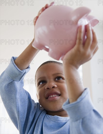 African American boy lifting piggy bank