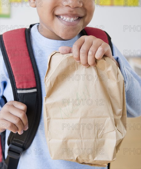 African American boy wearing backpack holding bag lunch