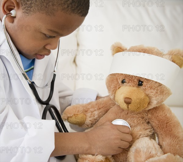 African American boy playing doctor with teddy bear