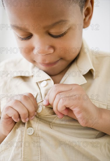 African American boy buttoning shirt