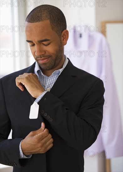 Mixed race shopper making face at price tag on jacket